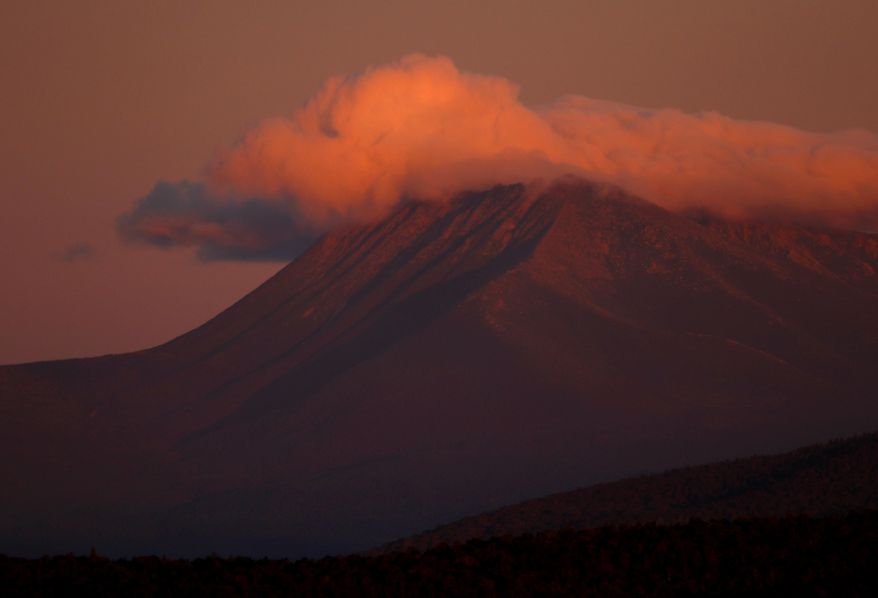 In this Monday, Aug. 7, 2017 photo, the first rays of sunlight color the clouds over Mount Katahdin in this view from the Katahdin Woods and Waters Scenic Byway outside Patten, Maine. Interior Secretary Ryan Zinke wants to retain the newly created Katahdin Woods and Waters National Monument in northern Maine, but said he might recommend adjustments to the White House on Thursday, Aug. 24, 2017. (AP Photo/Robert F. Bukaty)