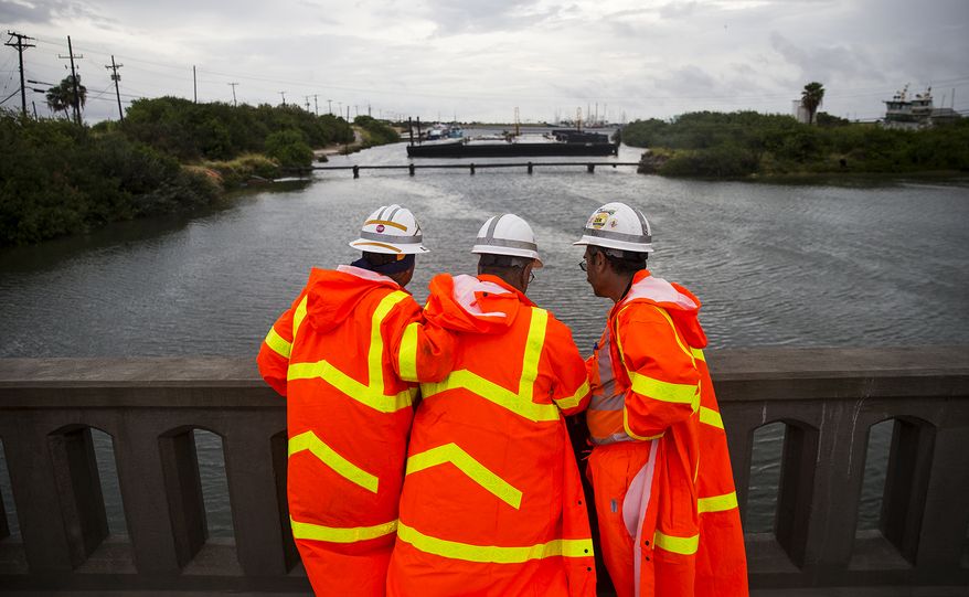 TxDOT crew members use a phone to check the radar while waiting to install the final portion of a surge wall on TX-361 leading to the Port Aransas ferry in preparation for Hurricane Harvey in Aransas Pass, Texas, on Friday, Aug. 25, 2017. Conditions deteriorated Friday along the Texas Gulf Coast as Hurricane Harvey strengthened and crawled toward the state, with forecasters warning that evacuations and preparations "should be rushed to completion." (Nick Wagner /Austin American-Statesman via AP)