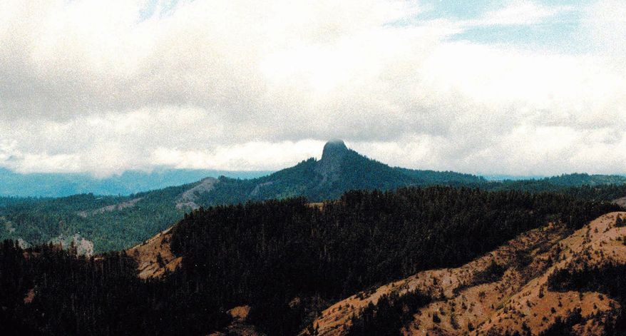 FILE- In this July 6, 2000, file photo, Pilot Rock rises into the clouds in the Cascade-Siskiyou National Monument near Lincoln, Oregon. Oregon and its political leaders await word on whether the Trump administration will shrink the Cascade-Siskiyou National Monument, a 112,000-acre monument along the border with California, Friday, Aug. 25, 2017. (AP Photo/Jeff Barnard, File)