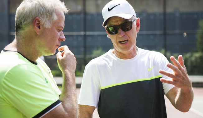 In this Tuesday, Aug. 22, 2017 photo Patrick and John McEnroe chat during scholarship tryouts for children ages 6 to 12 who are interested in attending the John McEnroe Tennis Academy in New York. (AP Photo/Michael Noble Jr.)