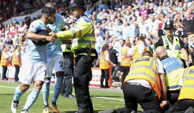 Manchester City&#x27;s Sergio Aguero is held back by police after going up the a stewards, right, who were dealing with a fan on the pitch after Raheem Sterling, not in picture, celebrates scoring his side&#x27;s second goal during the Premier League soccer match between AFC Bournemouth and Manchester City at the Vitality Stadium, Bournemouth, England. Saturday Aug 26, 2017. (Steve Paston /PA via AP)/PA via AP)