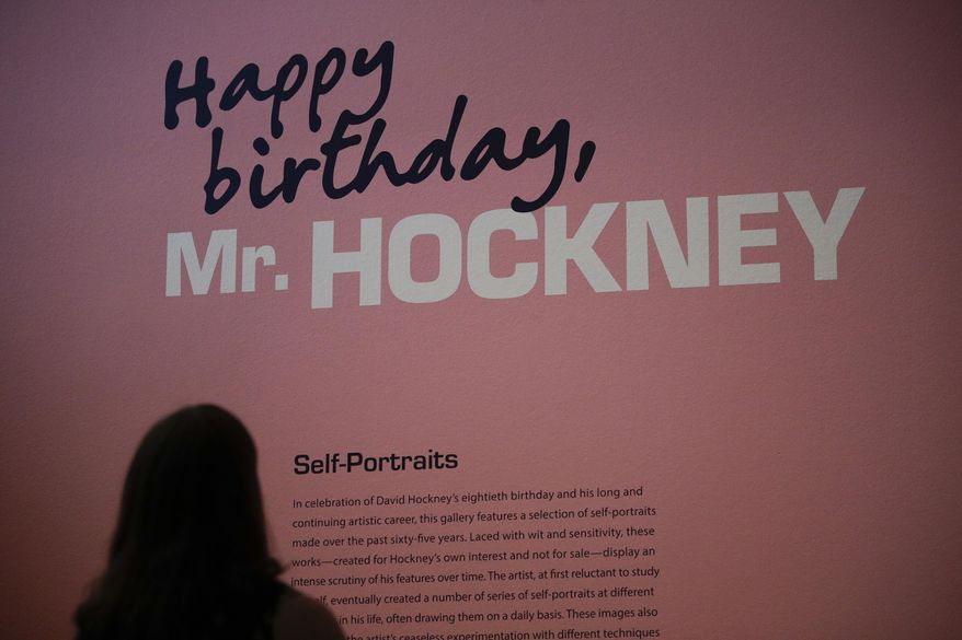 In this Wednesday, June 21, 2017 photo Alexandria Sivak, a senior communications specialist from J. Paul Getty Trust, reads a brief description of David Hockney's self-portraits in the exhibition hall at the Getty Center in Los Angeles. The aspiring artist was 17 when he took pencil to paper in 1954 and sketched out a stunningly mirror-like image of himself as a student at England's Bradford School of Art. In the 63 years since, David Hockney has become world famous not for self-portraits but colorful painted landscapes and brilliant photo collages of everything from backyard swimming pools to scenic desert vistas. (AP Photo/Jae C. Hong)