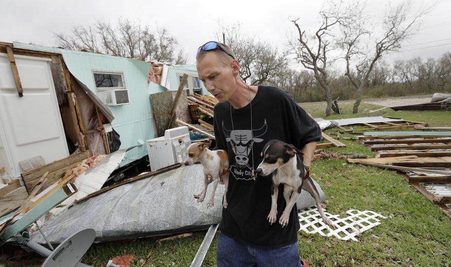 Sam Speights holds two of his dogs as he checks on the damage to his home in the wake of Hurricane Harvey, Sunday, Aug. 27, 2017, in Rockport, Texas. Speights tried to stay in his home during the storm but had to move to other shelter after his lost his roof and back wall. (AP Photo/Eric Gay)