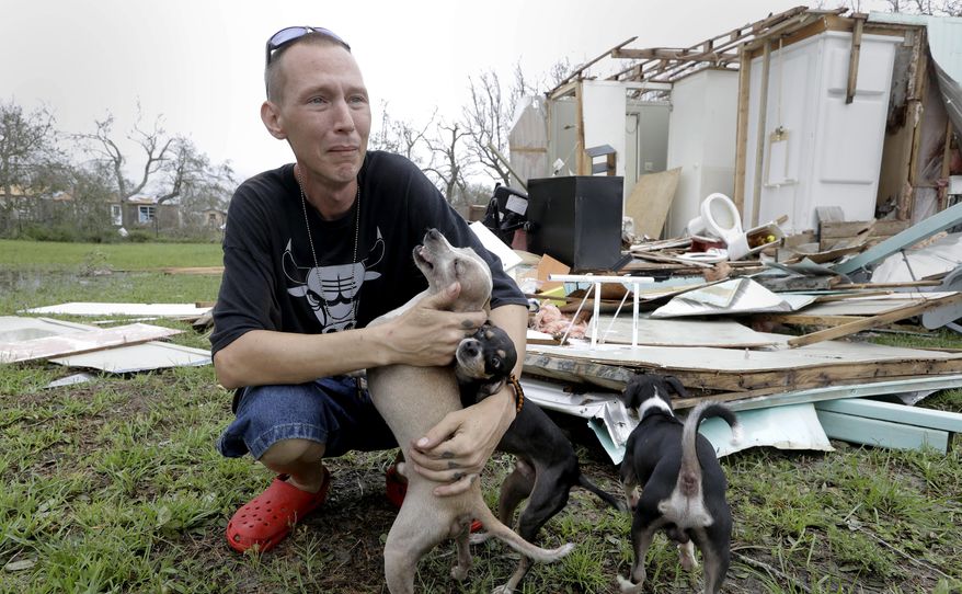 Sam Speights tries to hold back tears while holding his dogs and surveying the damage to his home in the wake of Hurricane Harvey, Sunday, Aug. 27, 2017, in Rockport, Texas. Speights tried to stay in his home during the storm but had to move to other shelter after he lost his roof and back wall. (AP Photo/Eric Gay)