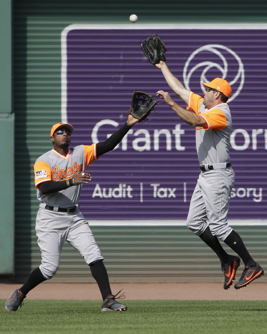 Baltimore Orioles' Seth Smith, right, leaps as he catches a fly ball by Boston Red Sox's Mookie Betts as Orioles' Adam Jones, left, backs him up in the fifth inning of a baseball game, Sunday, Aug. 27, 2017, in Boston. (AP Photo/Steven Senne)