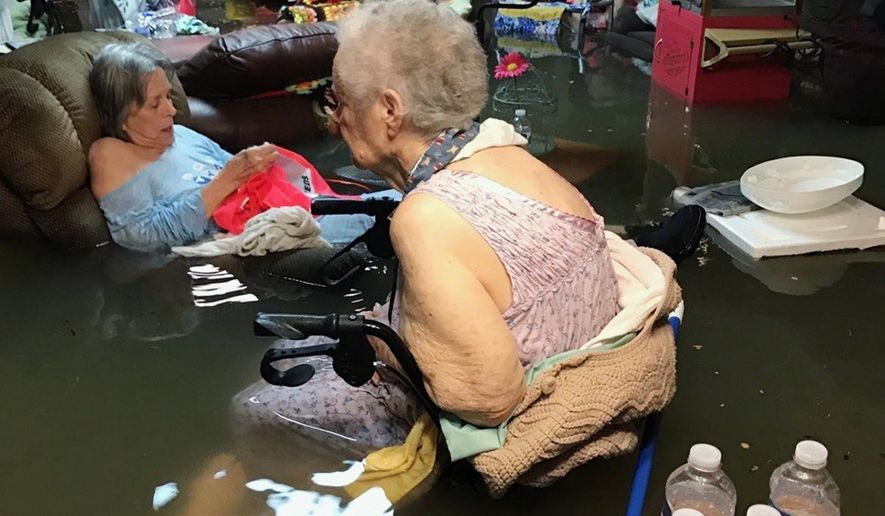 In this Sunday, Aug. 27, 2017, photo provided by Trudy Lampson, residents of the La Vita Bella nursing home in Dickinson, Texas, sit in waist-deep flood waters caused by Hurricane Harvey. Authorities said all the residents were safely evacuated from the facility. (Trudy Lampson via AP)