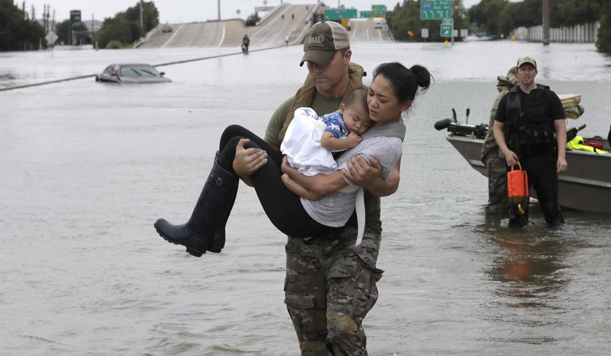 Houston Police SWAT officer Daryl Hudeck carries Catherine Pham and her 13-month-old son Aiden after rescuing them from their home surrounded by floodwaters from Tropical Storm Harvey Sunday, Aug. 27, 2017, in Houston. The remnants of Hurricane Harvey sent devastating floods pouring into Houston Sunday as rising water chased thousands of people to rooftops or higher ground. (AP Photo/David J. Phillip)