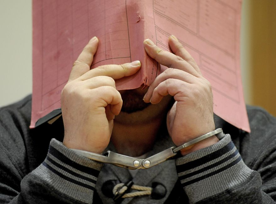 In this Dec. 9, 2014, file photo former nurse Niels Hoegel accused of multiple murder and attempted murder of patients, stands in the court room wearing handcuffs and covering his face with a file at the district court in Oldenburg, Germany. (Ingo Wagner/dpa via AP) ** FILE **