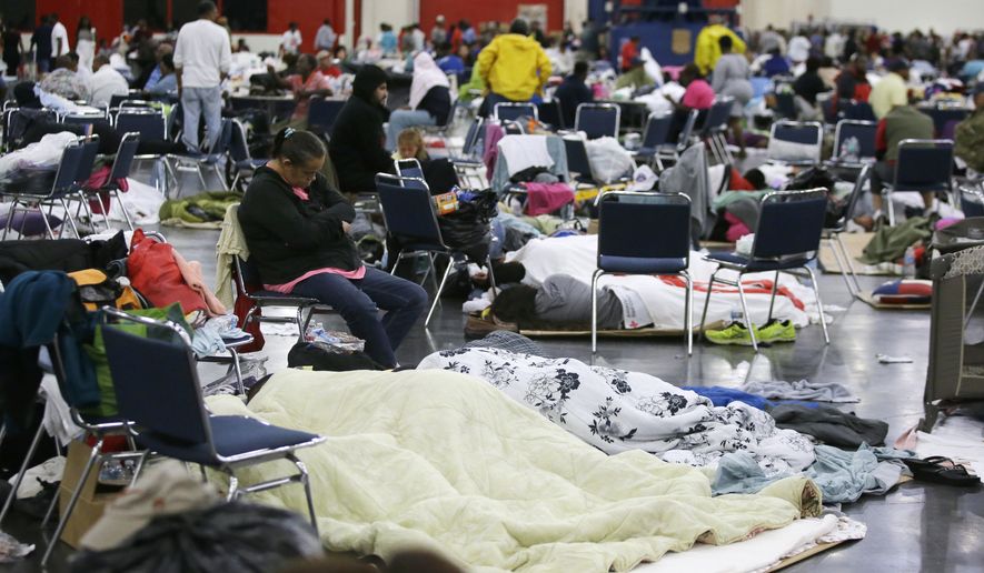 People rest at the George R. Brown Convention Center that has been set up as a shelter for evacuees escaping the floodwaters from Tropical Storm Harvey in Houston, Texas, Tuesday, Aug. 29, 2017. (AP Photo/LM Otero)