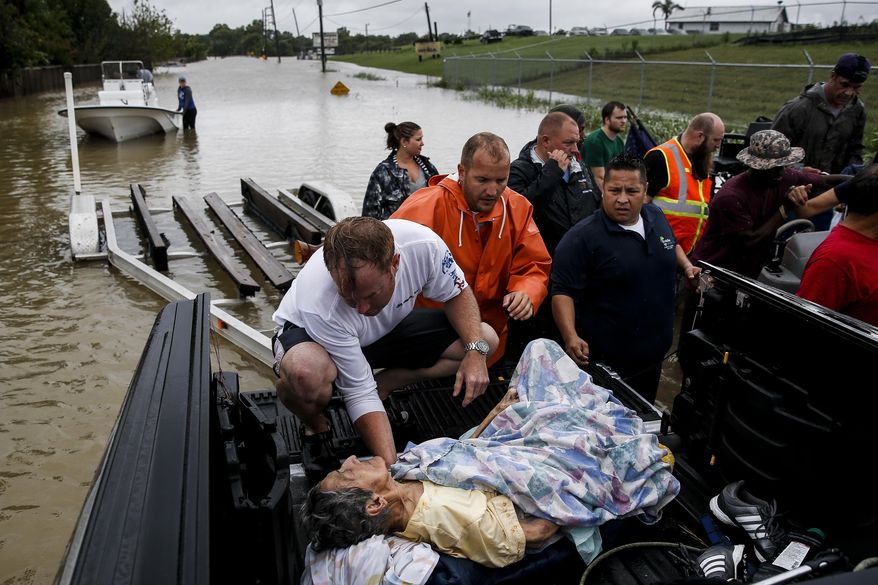 A rescuer moves Paulina Tamirano, 92, from a boat to a truck bed as people evacuate from rising waters from Tropical Storm Harvey, Tuesday, Aug. 29, 2017 in Houston. (Michael Ciaglo/Houston Chronicle via AP)