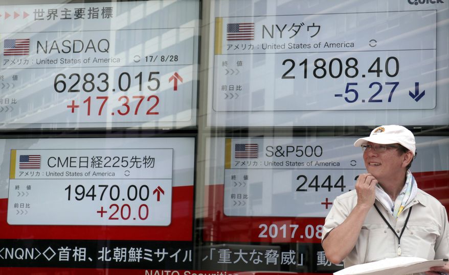A man walks past an electronic stock indicator of a securities firm in Tokyo, Tuesday, Aug. 29, 2017. Asian shares were mostly lower Tuesday, as the region was rattled by a ballistic missile launch in which the projectile flew over Japan and fell into the Pacific Ocean. (AP Photo/Shizuo Kambayashi)