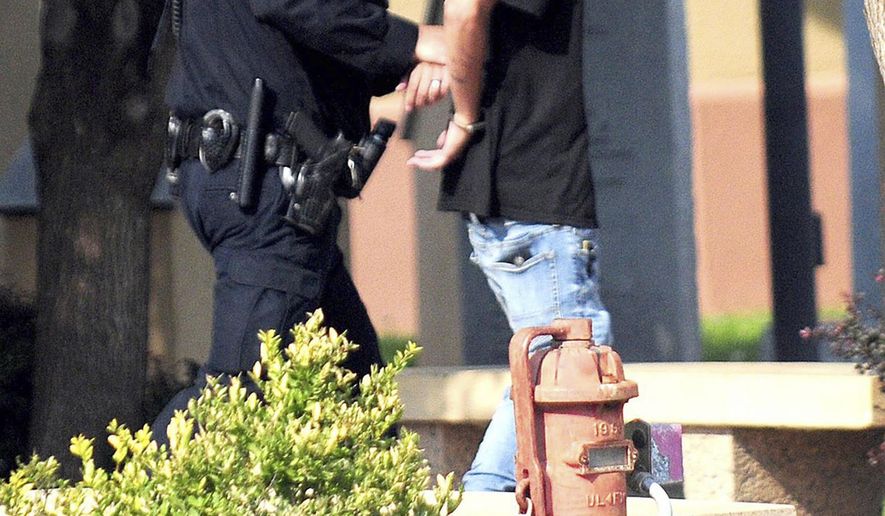 In this Monday, Aug. 28, 2017 photo, police take a man into custody after a shooting at a public library in the eastern New Mexico community of Clovis. Authorities on Tuesday identified the gunman accused of opening fire inside the library as a Nathaniel Jouett, 16-year-old high school student who they say killed a youth librarian and a second employee while wounding four others. The Associated Press generally does not identify juveniles accused of crimes, but is identifying Jouett because of the seriousness of the crime and because authorities said they plan to file a motion requesting the case's transfer from the juvenile system to adult court. (Tony Bullocks/Eastern New Mexico News via AP)