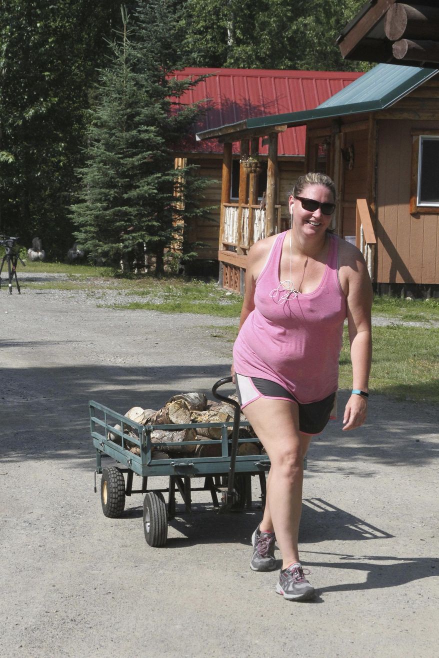 In this July 12, 2017, photo, Christie Stoltz is seen delivering firewood to a cabin at the Meandering Moose Lodging in Talkeetna, Alaska. Unlike her father, lodge owner Mike Stoltz, she is in favor of The High Expedition Co., the first marijuana shop in the quirky Alaska tourist town, which has caused a divide among town residents. (AP Photo/Mark Thiessen)