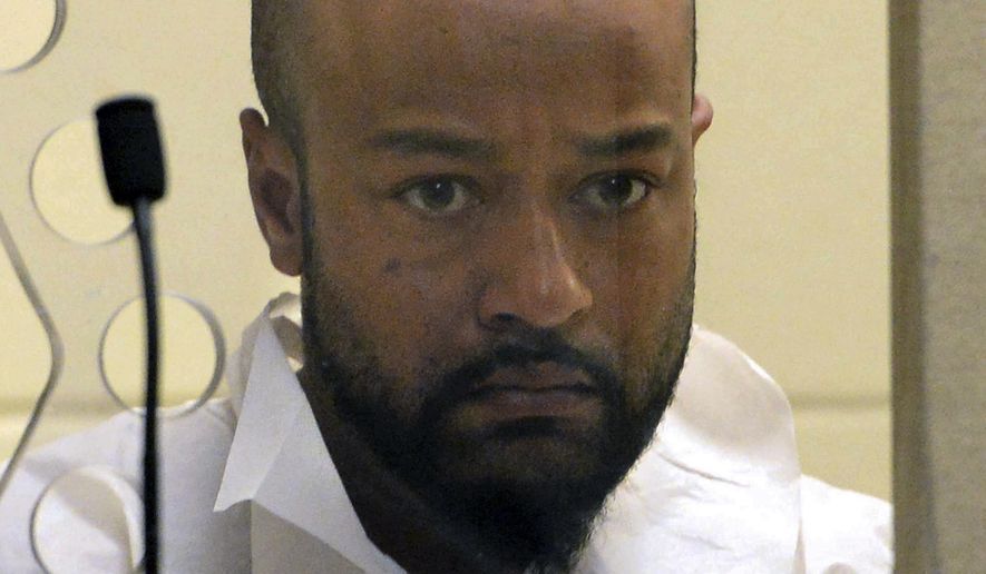 Daniel J. Lopes peers out from the defendant's box during his murder arraignment in Brockton District Court on Wednesday, Aug. 30, 2017. Lopes is charged in the murder of Julia Fernandes, 72, of West Bridgewater. (Marc Vasconcellos/The Enterprise via AP, Pool)