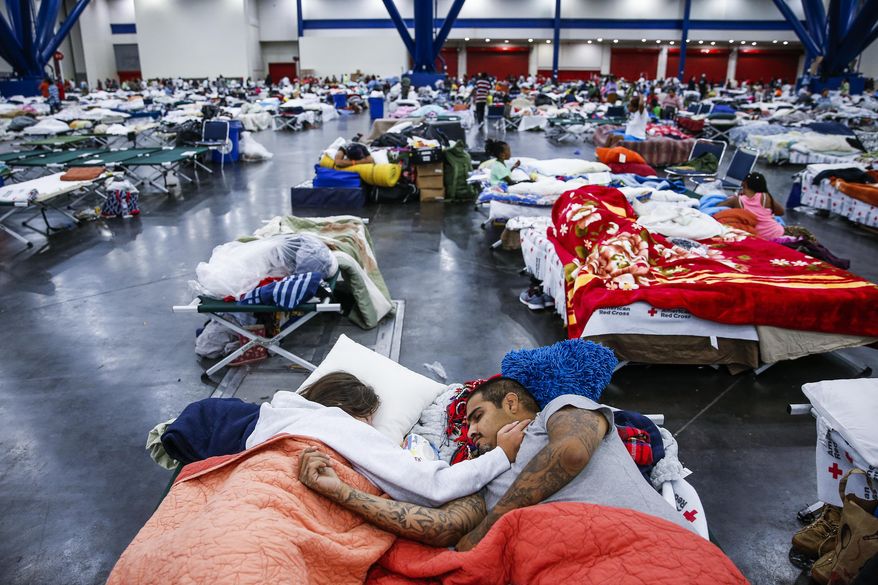 Tammy Dominguez, left, and her husband, Christopher Dominguez, sleep on cots at the George R. Brown Convention Center where nearly 10,000 people are taking shelter after Tropical Storm Harvey, Wednesday, Aug. 30, 2017, in Houston. They have been at the shelter since evacuating Houston's Northside on Sunday. (Michael Ciaglo/Houston Chronicle via AP)