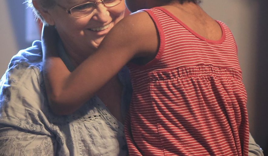 Tina Betzer holds Sophie Betzer, 13, as Jamine Betzer, 13, sits in her wheelchair at their home in Shelley, Id., Thursday, August 17, 2017. Sophie was born with a form of CHARGE syndrome, a genetic disorder which leads to Sophie having holes in her eyes, deformed sinuses, and deafness. Tina and Rick Betzer have adopted 16 children over the years-14 from foster care most with some sort of physical or mental handicap- and are worried about the impact cuts to medicaid would have on their ability to care for their children. Medicaid helps lower the out-of-pocket costs for things like formula, leg braces, wheelchairs, and transportation. (John Roark/ Post Register via AP)