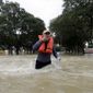 Mike Bialka holds a cigar as he makes his way through floodwaters from Tropical Storm Harvey to help a friend secure his home Wednesday, Aug. 30, 2017, in Kingwood, Texas. (AP Photo/Gregory Bull)