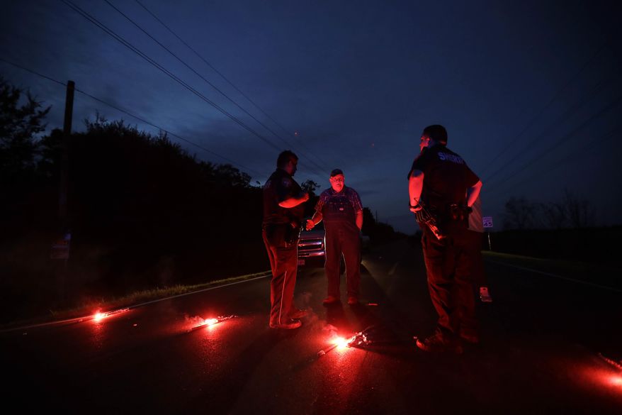A man talks with officers at a roadblock less than three miles from the Arkema Inc. chemical plant Thursday, Aug. 31, 2017, in Crosby, Texas. The Houston-area chemical plant that lost power after Harvey engulfed the area in extensive floods was rocked by multiple explosions early Thursday, the plant's operator said. The Arkema Inc. plant had been left without refrigeration for chemicals that become volatile as the temperature rises. (AP Photo/Gregory Bull)