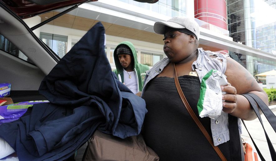 Hurricane Harvey evacuee Lakeithia Bankhead, accompanied by son Russell McCoy, tosses items into the back of a vehicle as she leaves a mass shelter in Houston bound for home on Friday, Sept. 1, 2017. Bankhead said her home was badly flooded and she is worried about potential health problems, but she didn't get cleaning supplies or the know-how to deal with possible threats. (AP Photo/Jay Reeves)
