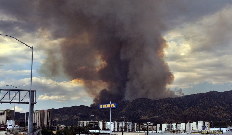 Heavy black smoke rises as a wildfire burns dozens of acres in the Tujunga area of Los Angeles, seen from nearby Burbank, Calif., Friday afternoon, Sept. 1, 2017. Subdivisions full of houses are within a mile of the flames, and residents of three streets have been told to evacuate. (AP Photo/Richard Vogel)