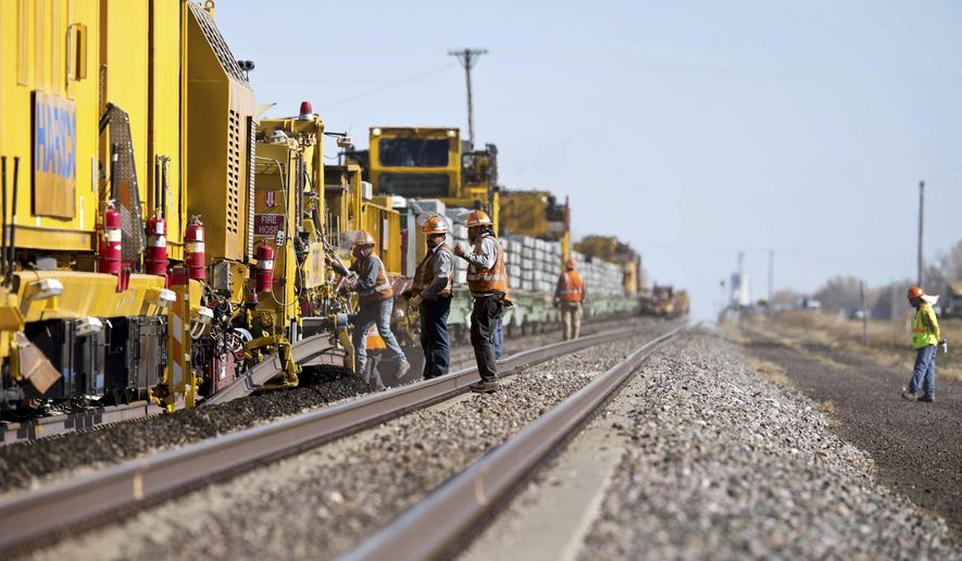 In this Oct. 16, 2012 photo, workers for Union Pacific operate a track renewal train in Grand Island, Neb. Union Pacific Railroad's recent decision to trim 750 positions, mainly at its Omaha headquarters, follows similar force reductions by the other major freight rail systems. (Ryan Soderlin/Omaha World-Herald via AP)