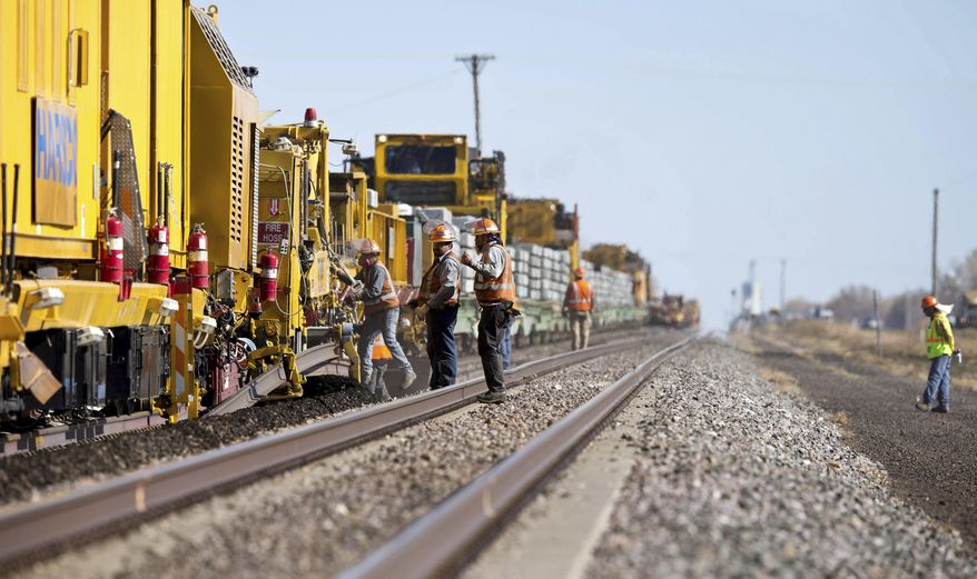 In this Oct. 16, 2012 photo, workers for Union Pacific operate a track renewal train in Grand Island, Neb. Union Pacific Railroad's recent decision to trim 750 positions, mainly at its Omaha headquarters, follows similar force reductions by the other major freight rail systems. (Ryan Soderlin/Omaha World-Herald via AP)