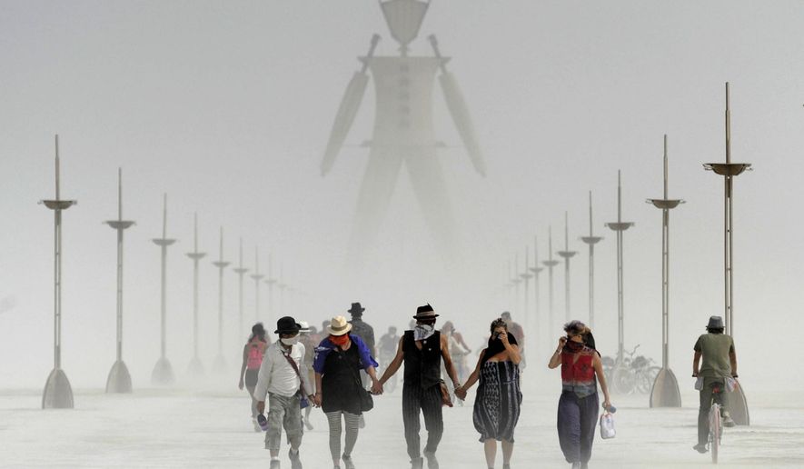In this Aug. 29, 2014, file photo, Burning Man participants walk through dust at the annual Burning Man event on the Black Rock Desert of Gerlach, Nev. A Nevada sheriff says a man who ran into the flames at the Burning Man festival's signature burning ceremony has died. Pershing County Sheriff Jerry Allen identified the man as Aaron Joel Mitchell, 41, who died Sunday, Sept. 3, 2017, morning at the UC Davis hospital burn center in California. (Andy Barron/The Reno Gazette-Journal via AP, File)