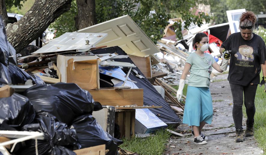 Jenny Killingsworth, right, holds the hand of Janeah Tieman, 10, while helping clean up a home damaged by floodwaters in the aftermath of Hurricane Harvey on Monday, Sept. 4, 2017, in Houston. (AP Photo/David J. Phillip)