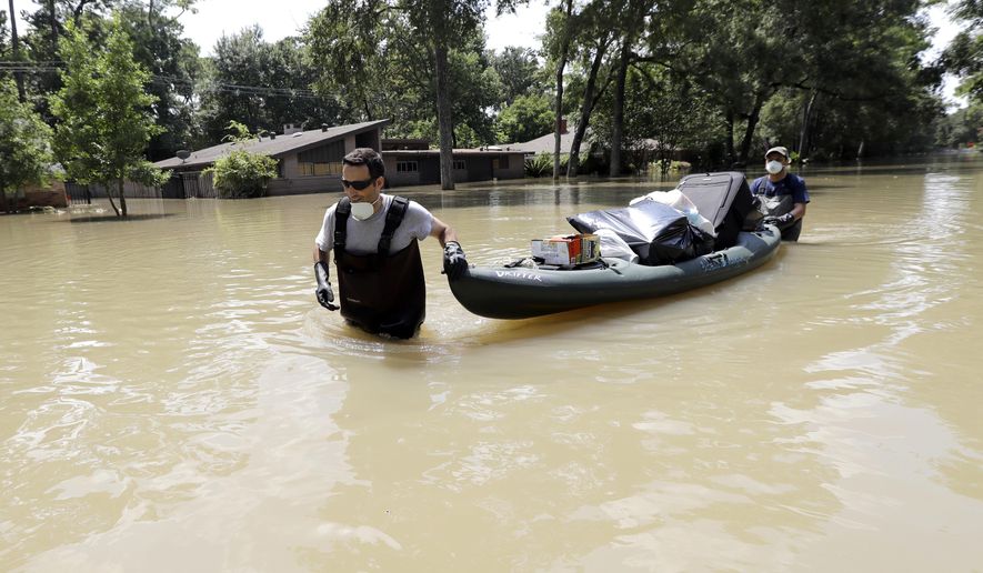 Gaston Kirby, left, is helped by friend Juan Minutella after gathering the last of his belongings from his flooded home in the aftermath of Hurricane Harvey Monday, Sept. 4, 2017, near the Addicks and Barker Reservoirs, in Houston. (AP Photo/David J. Phillip)