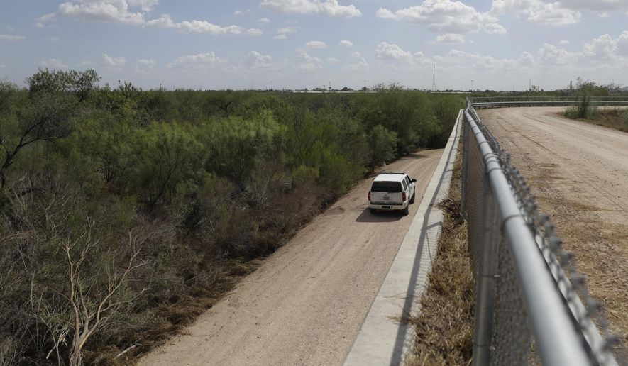 In this Aug. 11, 2017, photo, a U.S. Customs and Border Patrol agent passes along a section of border levee wall in Hidalgo, Texas. The government wants to build on the 3 miles (5 kilometers) of river levee cutting through the northern edge of the Santa Ana National Wildlife Refuge, separating the visitor center from the rest of the park. A gate in the wall would open and close for visitors. (AP Photo/Eric Gay)