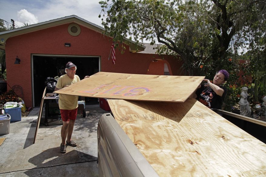 Stan Kreuter, 71, left, and his wife Jackie Kreuter, 56, Gulfport, Fla.,, load plywood in front of their home to take to their downtown Gulfport store Tuesday, Sept. 5, 2017, so they can board it up. Jackie Kreuter, along with her mother, husband, sister, daughter, grandson, five dogs and a bird are boarding up their home and business and leaving for Ocala to get out of Hurricane Irma's way. (Lara Cerri/The Tampa Bay Times via AP)