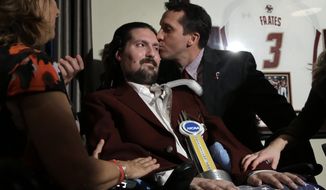 FILE - In this Dec. 13, 2016, file photo, former Boston College baseball captain Pete Frates, center left, receives a kiss from Boston College head baseball coach Mike Gambino after Frates was presented with the 2017 NCAA Inspiration Award, during ceremonies in Frates home in Beverly, Mass. The man who inspired the ice bucket challenge that has raised millions for ALS research is being honored at Boston City Hall. Mayor Martin Walsh is hosting a rally Tuesday, Sept. 5, 2017, for Frates at City Hall Plaza. The event coincides with the release of a new book on Frates. (AP Photo/Steven Senne, File)