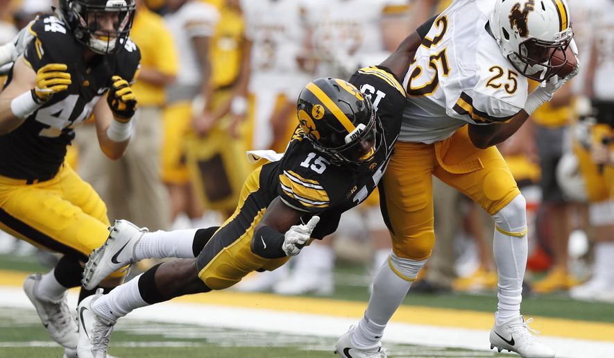 Wyoming wide receiver Austin Conway (25) is tackled by Iowa defensive back Joshua Jackson (15) after making a reception during the first half of an NCAA college football game, Saturday, Sept. 2, 2017, in Iowa City, Iowa. Iowa won 24-3. (AP Photo/Charlie Neibergall)