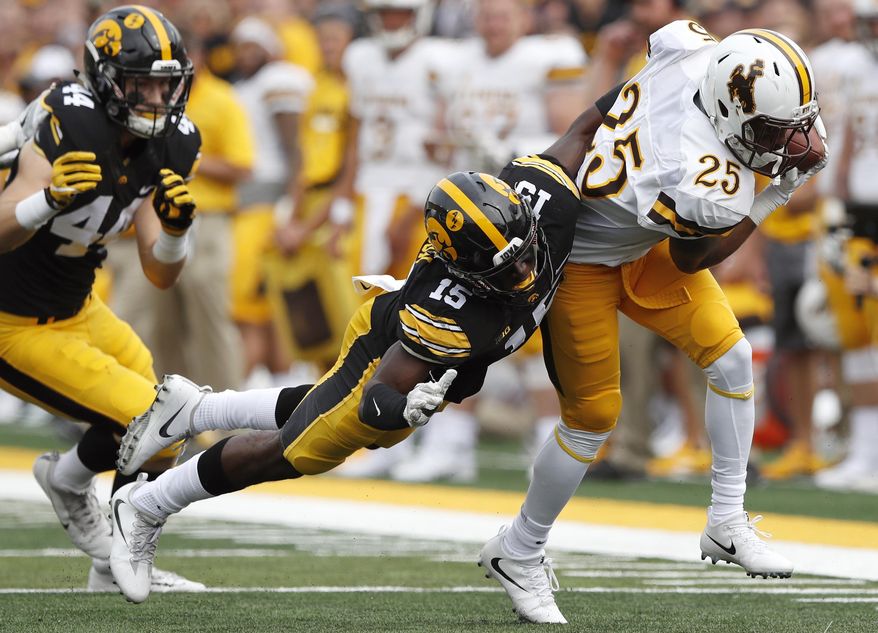 Wyoming wide receiver Austin Conway (25) is tackled by Iowa defensive back Joshua Jackson (15) after making a reception during the first half of an NCAA college football game, Saturday, Sept. 2, 2017, in Iowa City, Iowa. Iowa won 24-3. (AP Photo/Charlie Neibergall)