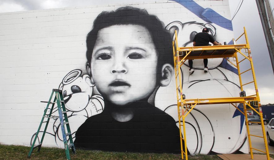 In this Aug. 31, 2017 photo, Eddie Fernandez works on a spray-painted mural of Silas Ojeda on the side of the Cheyenne Stitch building in Cheyenne, Wyo. A local man was sentenced to prison for killing the 13-month-old earlier this year, and Fernandez was commissioned to do the mural by Silas' step-grandmother. (Jacob Byk/The Wyoming Tribune Eagle via AP)