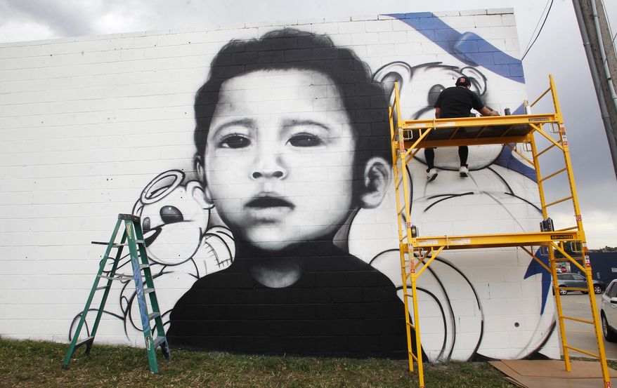 In this Aug. 31, 2017 photo, Eddie Fernandez works on a spray-painted mural of Silas Ojeda on the side of the Cheyenne Stitch building in Cheyenne, Wyo. A local man was sentenced to prison for killing the 13-month-old earlier this year, and Fernandez was commissioned to do the mural by Silas' step-grandmother. (Jacob Byk/The Wyoming Tribune Eagle via AP)