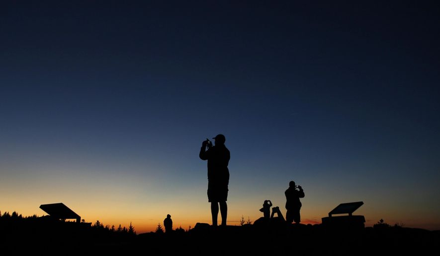 FILE - In this Oct. 2, 2014, file photo, tourists photograph the sunset at the summit of Cadillac Mountain in Acadia National Park near Bar Harbor, Maine. The nearby Jordan Pond Shore Trail offers stunning views and a way to get your steps in while enjoying the foliage. (AP Photo/Robert F. Bukaty, File)