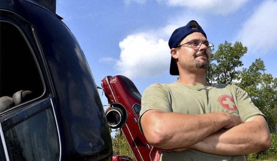 ADVANCE FOR SATURDAY SEPT. 9 AND THEREAFTER - Bill Janowsky stands near cars he recently buried on property at Wild Bill's Auto Parts in Merrillville, Ind. Bill and his father took over the family business about a month ago after a relative's death. The two have been trying to figure out how to drive in more customers to their 18-or-so acres of roughly 300 cars. William Janowsky said he had a "crazy thought" to "get attention," and Tim Janowsky told him to "go for it." ( Joe Puchek/The Post-Tribune via AP)