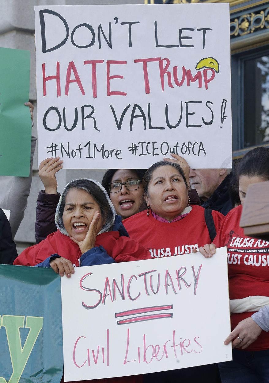 FILE In this Jan. 25, 2017 file photo protesters hold signs as they yell at a rally outside of City Hall in San Francisco. Hundreds of bills await action by California lawmakers as the Legislature begins the last week of business this year. Among the issues is the so-called sanctuary state bill, which would restrict state and local aw enforcement agencies from cooperating with federal immigration authorities. (AP Photo/Jeff Chiu,file)