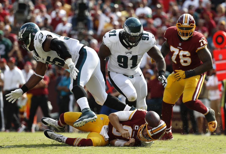 Washington Redskins quarterback Kirk Cousins, bottom, fumbles in front of Philadelphia Eagles defensive tackle Fletcher Cox (91), defensive end Brandon Graham, left, and Redskins offensive tackle Morgan Moses (76) in the second half of an NFL football game, Sunday, Sept. 10, 2017, in Landover, Md. Cox recovered the fumble and scored a touchdown on the play. Philadelphia won 30-17. (AP Photo/Alex Brandon)
