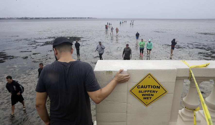 People walk out onto what is normally four feet of water in Old Tampa Bay, Sunday, Sept. 10, 2017, in Tampa, Fla. Hurricane Irma and an unusual low tide pushed water out over 100 yards. (AP Photo/Chris O&#39;Meara)