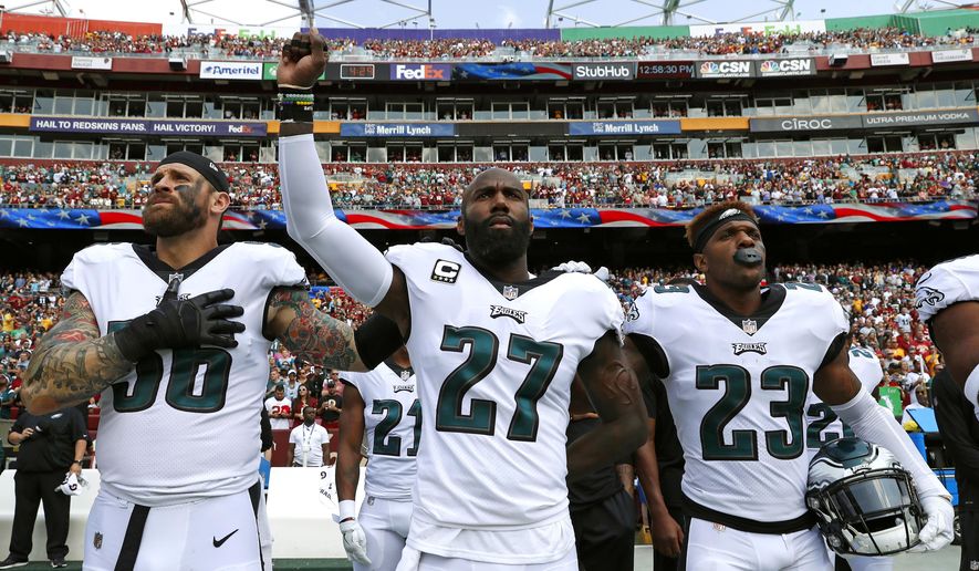 Philadelphia Eagles strong safety Malcolm Jenkins, center, raises his fist as he stands between teammates Chris Long, left, and Rodney McLeod during a rendition of the national anthem before an NFL football game against the Washington Redskins, Sunday, Sept. 10, 2017, in Landover, Md. (AP Photo/Alex Brandon)