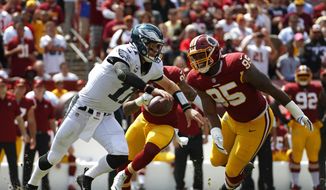 Philadelphia Eagles quarterback Carson Wentz, left, tries to outrun Washington Redskins defensive end Jonathan Allen (95) and outside linebacker Preston Smith as he looks for a receiver in the first half of an NFL football game, Sunday, Sept. 10, 2017, in Landover, Md. (AP Photo/Alex Brandon) **FILE**