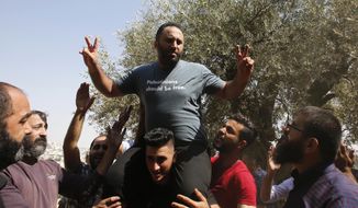 Palestinian activist Issa Amro, center, celebrates his release from detention, in the West Bank city of Hebron, Sunday, Sept. 10, 2017. The Palestinian Authority has released Amro a week after he was arrested for writing a Facebook post criticizing the government of President Mahmoud Abbas. (AP Photo/Nasser Shiyoukhi)
