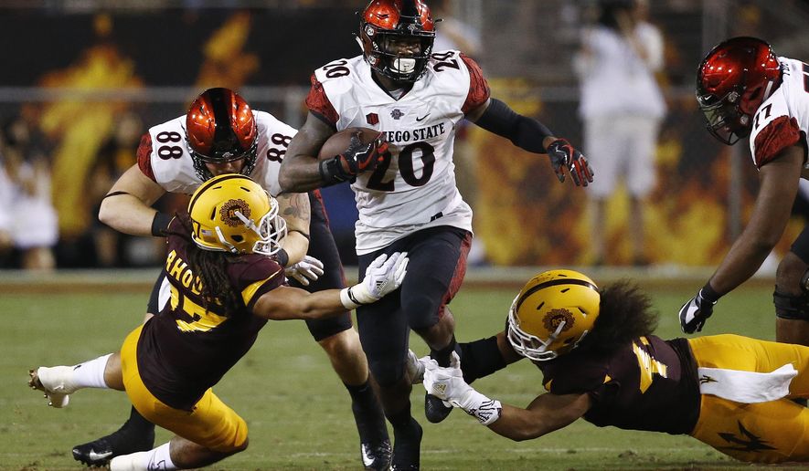 San Diego State's Rashaad Penny (20) runs with the ball as Arizona State's J'Marcus Rhodes, left, and Alani Latu, right, move in to make the tackle as San Diego State's David Wells (88) tries to block Rhodes during the first half of an NCAA college football game Saturday, Sept. 9, 2017, in Tempe, Ariz. (AP Photo/Ross D. Franklin)
