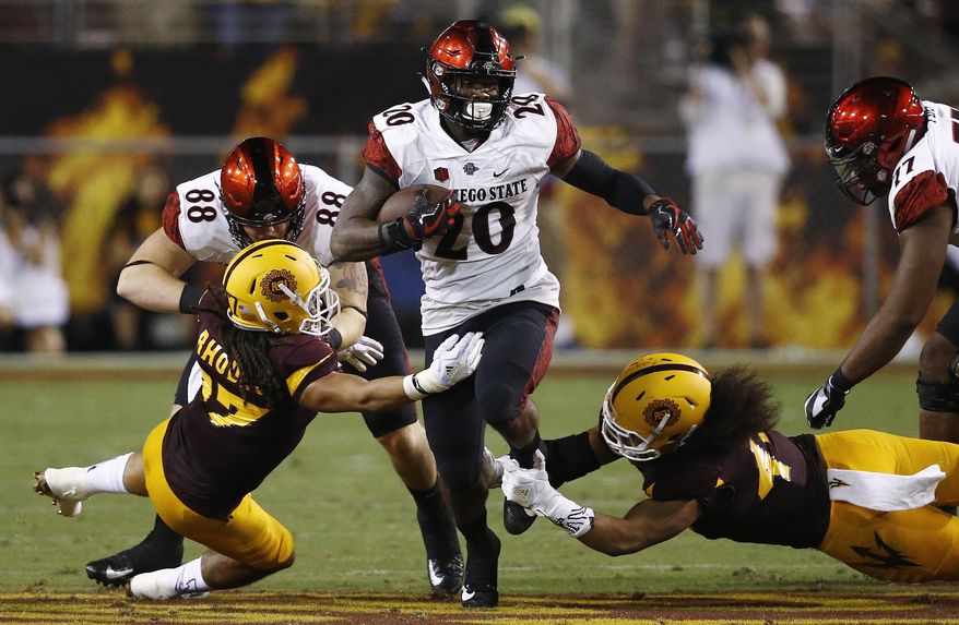 San Diego State's Rashaad Penny (20) runs with the ball as Arizona State's J'Marcus Rhodes, left, and Alani Latu, right, move in to make the tackle as San Diego State's David Wells (88) tries to block Rhodes during the first half of an NCAA college football game Saturday, Sept. 9, 2017, in Tempe, Ariz. (AP Photo/Ross D. Franklin)