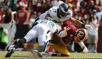 Washington Redskins quarterback Kirk Cousins, bottom right, slides as he is pressured by Philadelphia Eagles defensive tackle Destiny Vaeao, top, and outside linebacker Nigel Bradham in the second half of an NFL football game, Sunday, Sept. 10, 2017, in Landover, Md. (AP Photo/Alex Brandon)