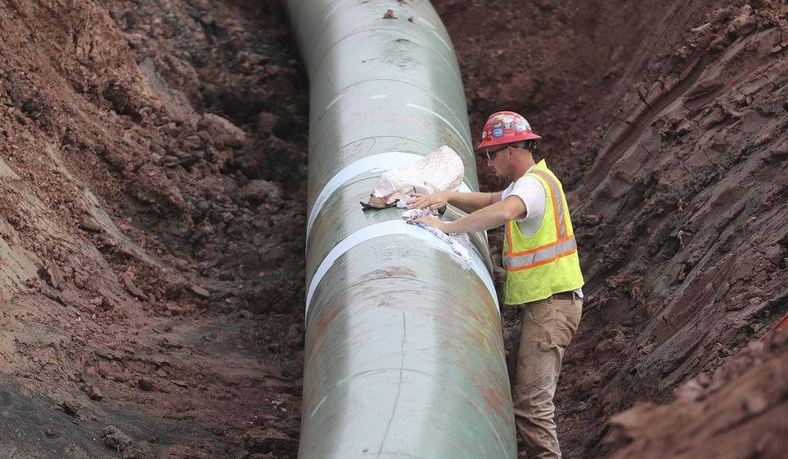 In an Aug. 21, 2017 photo, a pipe fitter lays the finish finishing touches to the replacement of Line 3 stretch before it is covered up. Enbridge already has started building the 14-mile stretch of Line 3 from the Minnesota line to its terminal in Superior, Wis. In filings with the Public Utilities Commission Monday, Sept. 11, The Minnesota Department of Commerce says Enbridge Energy has failed to establish the need for its proposal to replace its aging Line 3 crude oil pipeline across northern Minnesota. Instead, the department says it might be better to just shut down the existing line.  (Richard Tsong-Taatarii/Star Tribune via AP)
