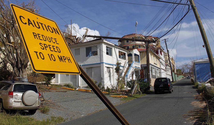 A speed limit sign stands tilted and a power line that snapped it half lays on a building, after the passage of Hurricane Irma in Charlotte Amalie, St. Thomas, U.S. Virgin Islands, Sunday, Sept. 10, 2017. The storm ravaged such lush resort islands as St. Martin, St. Barts, St. Thomas, Barbuda and Anguilla. (AP Photo/Ricardo Arduengo)