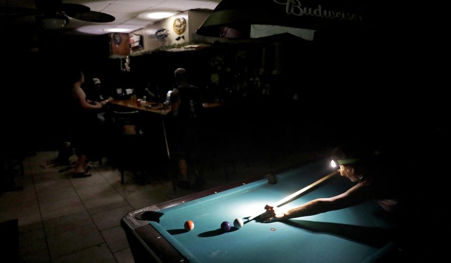 Lisa Borruso plays pool using a headlamp as the power remains out following Hurricane Irma at Gators' Crossroads in Naples, Fla., Monday, Sept. 11, 2017. Statewide, an estimated 13 million people, or two-thirds of Florida's population, remained without power. That's more than the population of New York and Los Angeles combined. Officials warned it could take weeks for electricity to be restored to everyone. (AP Photo/David Goldman)